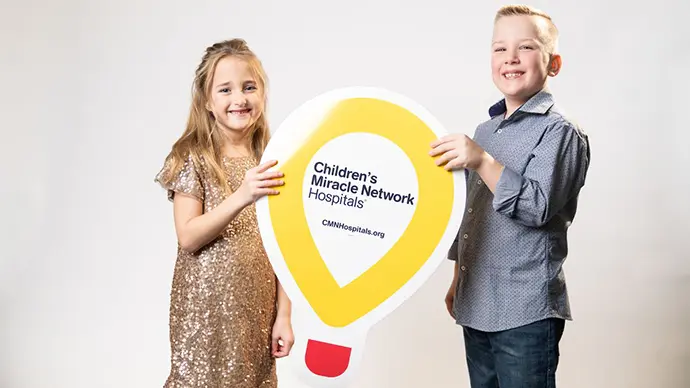 Kate and Ben Harkness holding Children's Miracle Network sign