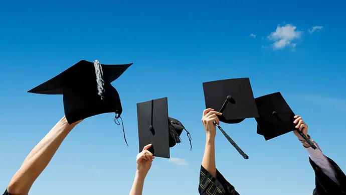 Students holding up graduation caps