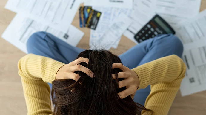 Woman stressed about a lot of credit card debt and bills on the floor.