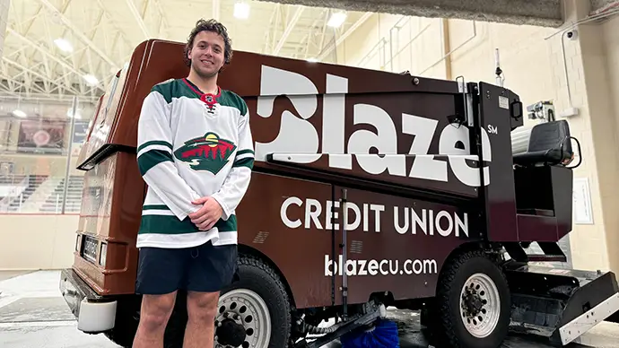 Brock Faber smiles next a Blaze Credit Union zamboni